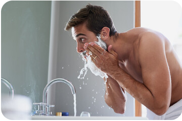 Un homme se rince le visage à l'eau après s'être rasé la barbe